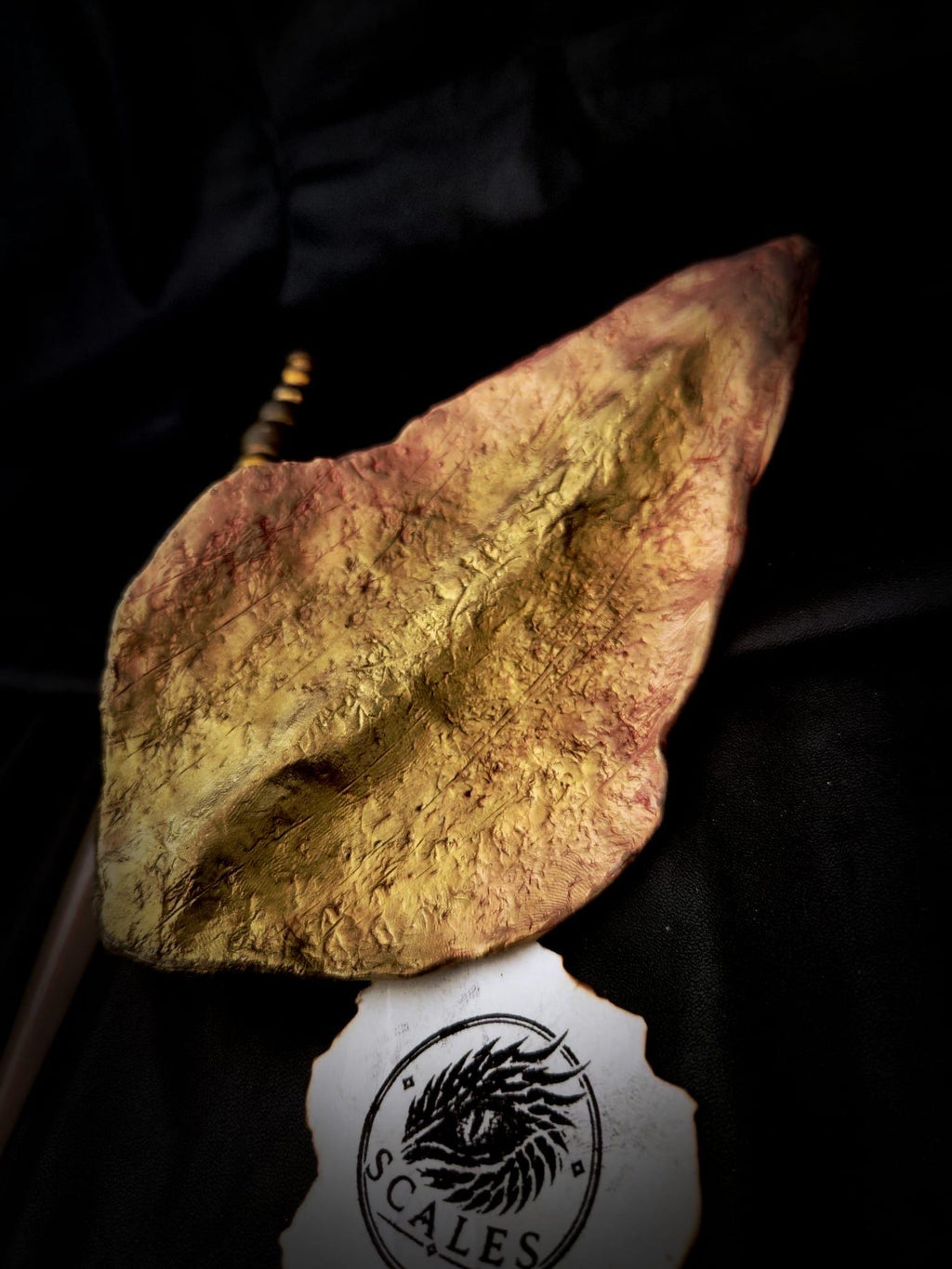 Détail des reliefs et reflets dorés et rosés de l’écaille de Sunfyre